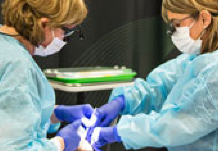 Two dentists wearing masks and gloves conducting a sealant prodecure
